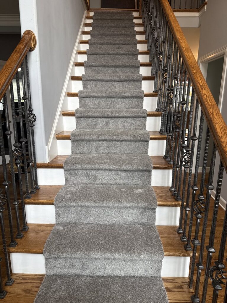 A beautifully installed gray carpet runner on a wooden staircase by NPN Flooring in Brookfield, IL.