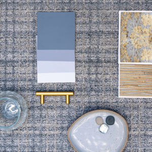 A flat lay showing a gray carpet sample with coordinating color swatches and decor from Jerry's Carpet Sales and Service in York, PA.