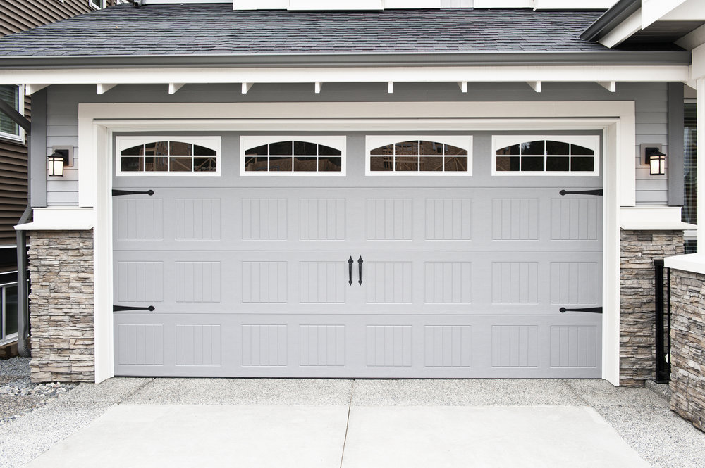 An elegant gray carriage-style garage door with decorative hardware and arched windows by Calavera Garage Doors in Mesa, AZ