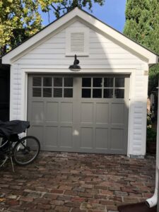 A newly installed gray garage door with windows on a white garage by Precision Garage Door of Charleston in Charleston, SC.