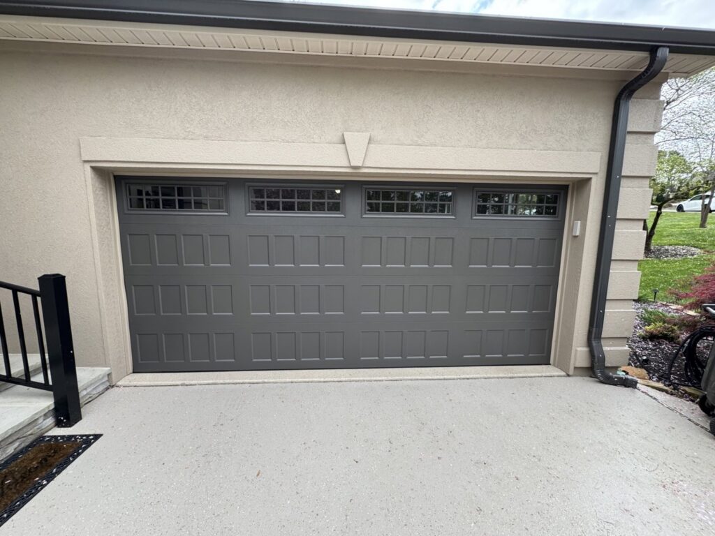 A gray garage door with multiple window inserts installed on a stucco house by Skylift Garage Doors - Knoxville, TN