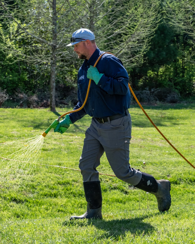A Great Lawns Turf Care technician spraying a lawn with a hose, providing turf care services in Nashville, TN.