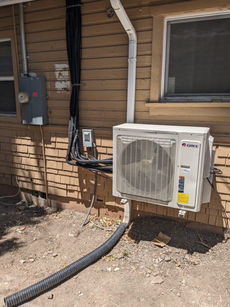 An exterior Gree mini-split outdoor unit with conduit installed by Inspector Rogers LLC in Draper, UT.