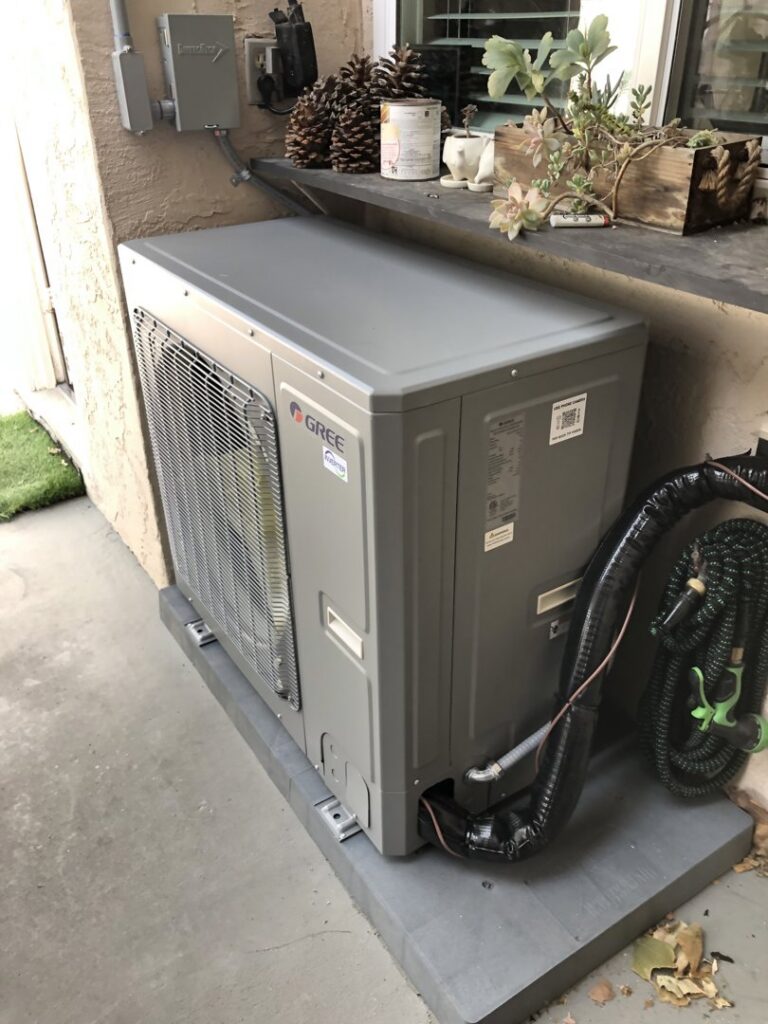A Gree outdoor mini-split condenser unit installed next to a home by Peace & Comfort Heating and Air in San Diego, CA.