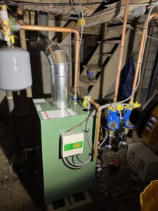 A green boiler unit with extensive copper piping installed by Russell Climate Solutions in Schenectady, NY.