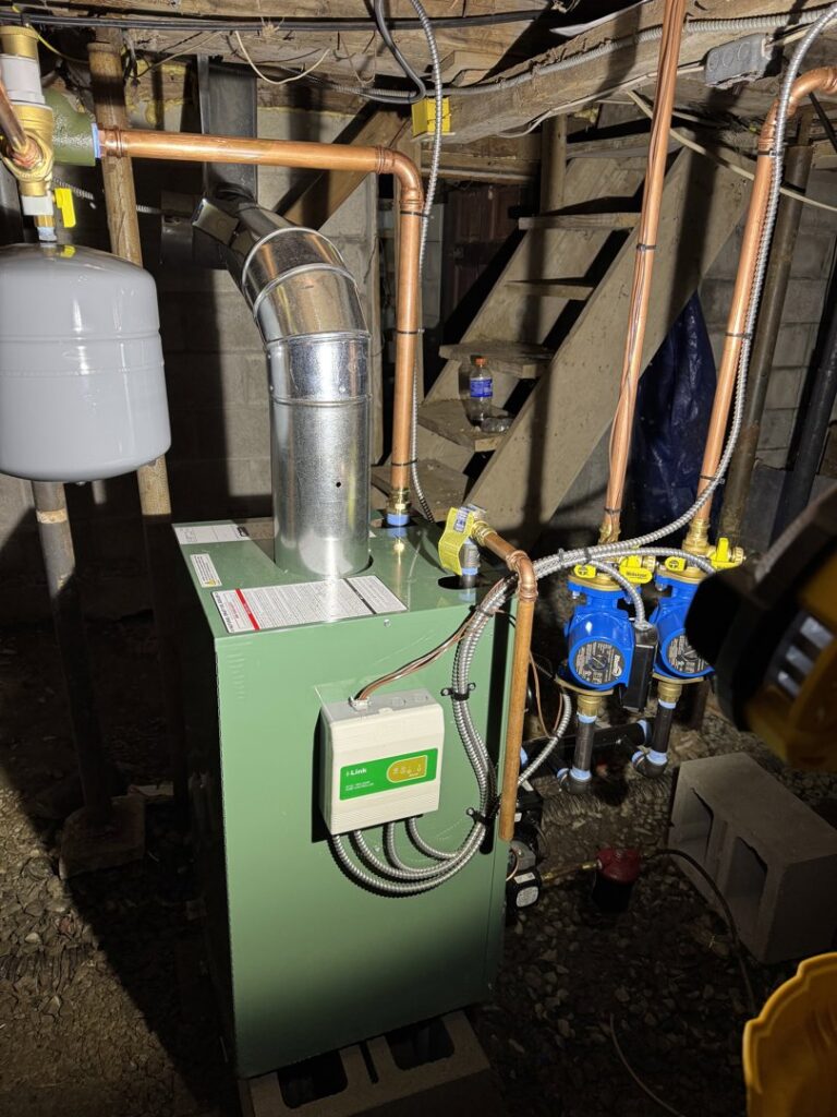 A green boiler unit with extensive copper piping installed by Russell Climate Solutions in Schenectady, NY.