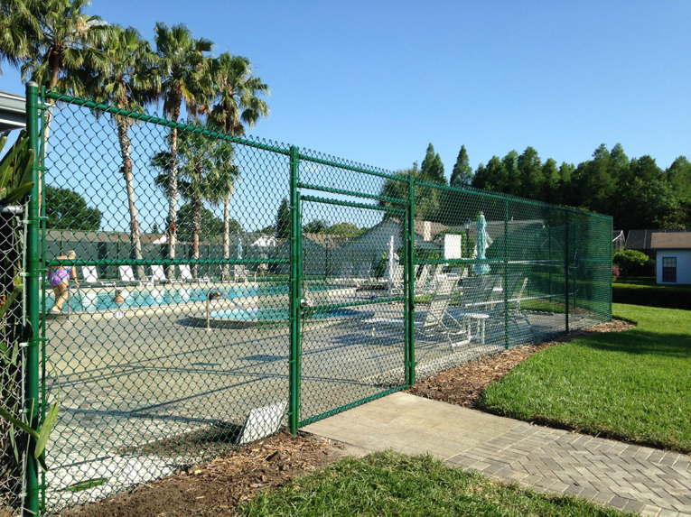 A green chain-link fence enclosing a swimming pool area, installed by Hernandez Fence in Orlando, FL.