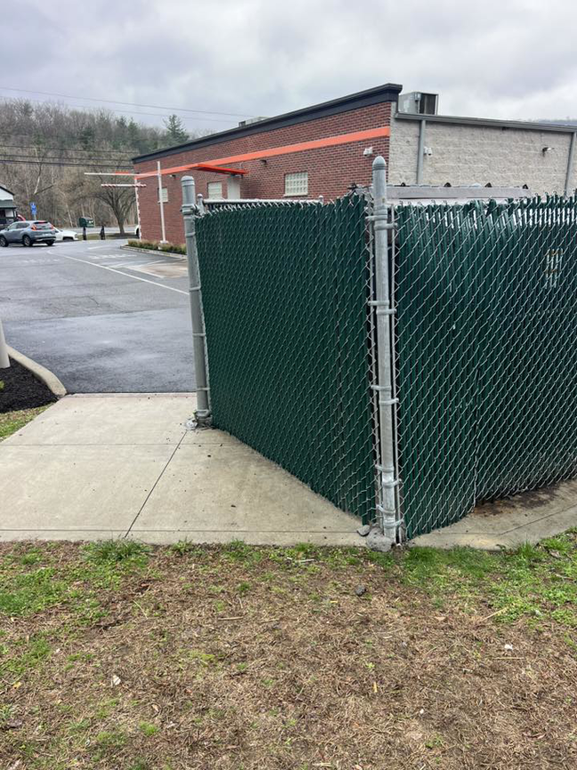 A newly installed green chain-link fence with privacy slats by Oxford Fence Company in Oxford, CT.