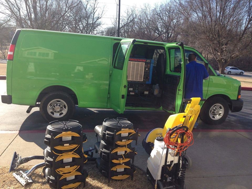 A green cleaning van with professional carpet cleaning equipment laid out, ready for a job by Martin Pro Cleaner in Tulsa, OK