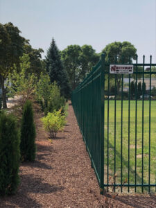 A green ornamental fence installed along a landscaped area by Northway Fence in Menomonee Falls, WI.