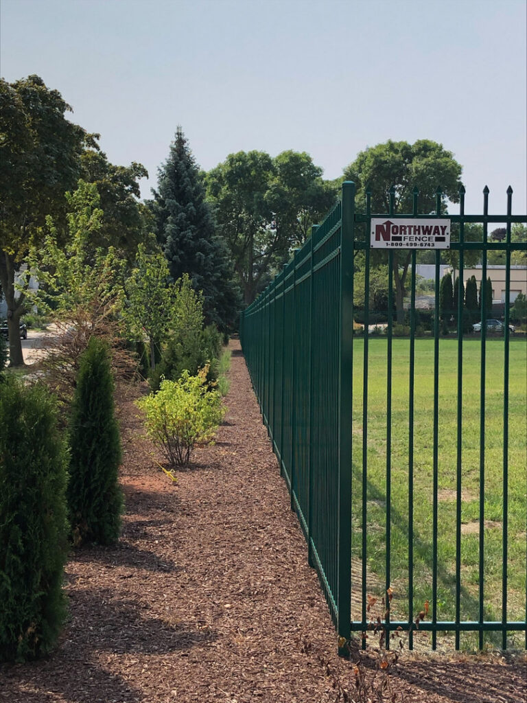 A green ornamental fence installed along a landscaped area by Northway Fence in Menomonee Falls, WI.