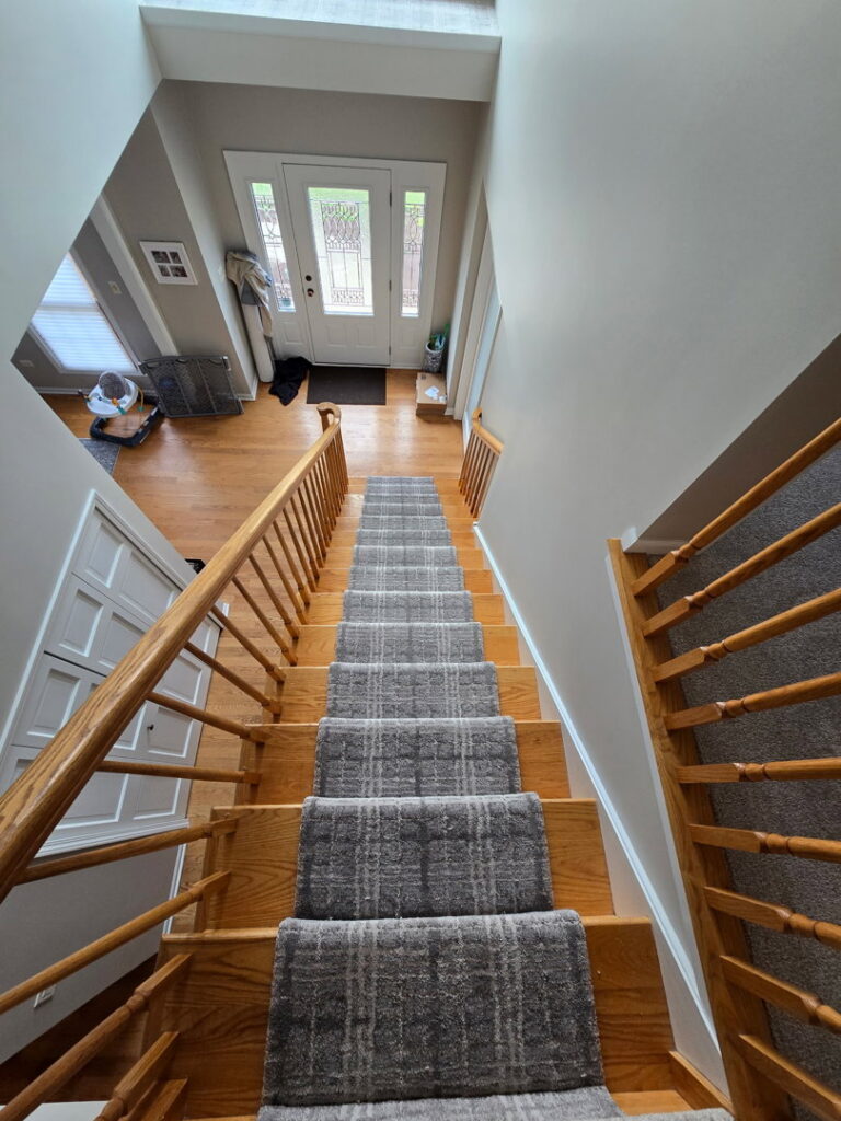 A newly installed grey carpet runner on wooden stairs by At Home Flooring in Naperville, IL.