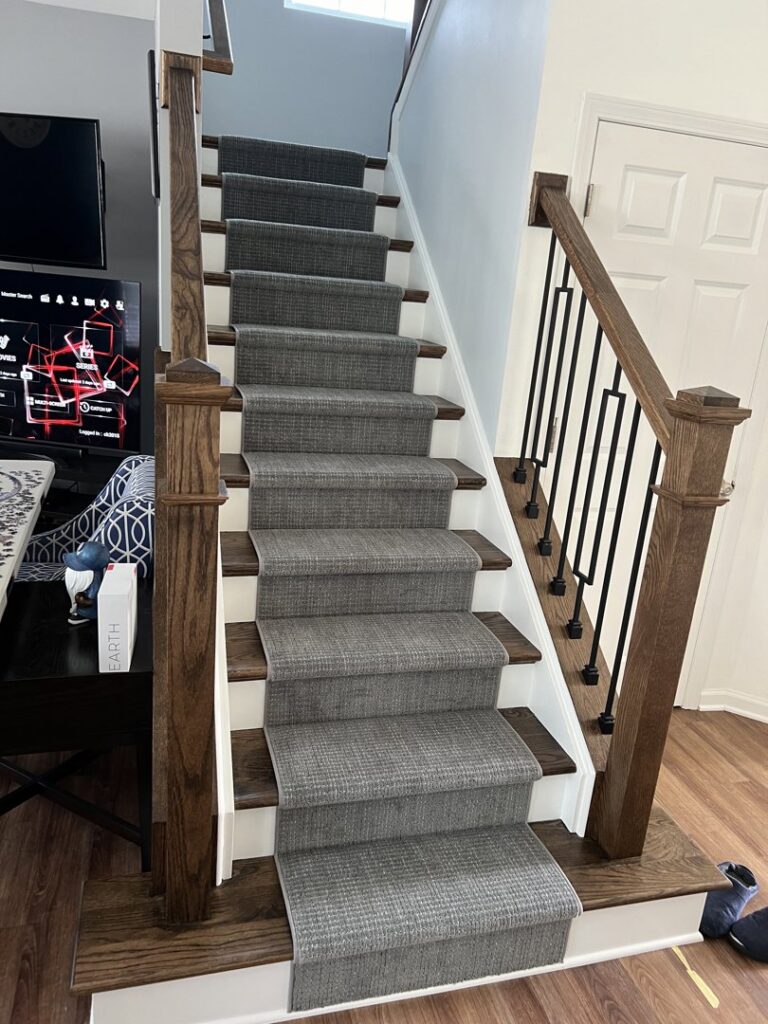 A modern grey carpet runner expertly installed on a wooden staircase by Rosas Carpet & Flooring in Shorewood, IL.