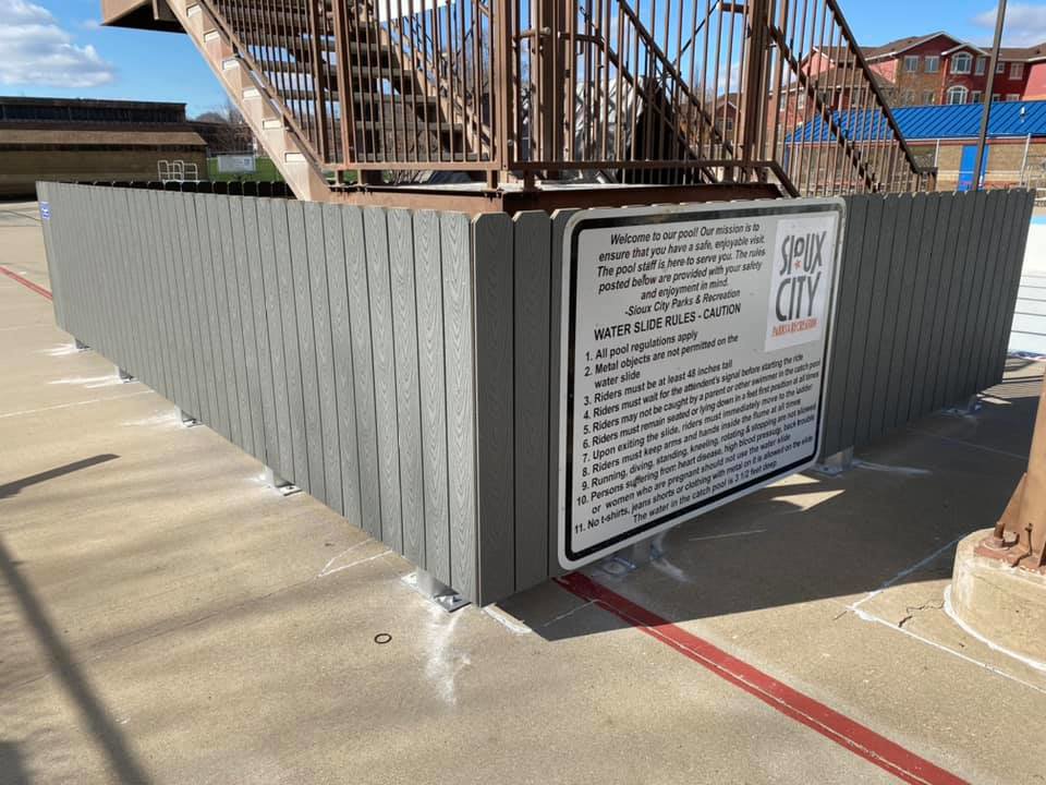 A grey composite privacy fence installed around a public pool area by Bostwick Fencing, LLC in Sioux City, IA.