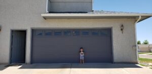 A newly installed grey panel garage door with top windows on a residential home by Prutch's Garage Door in Page, AZ