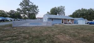 A grey picket fence enclosing a residential backyard and pool area, installed by Render Fences in Fishers, IN.