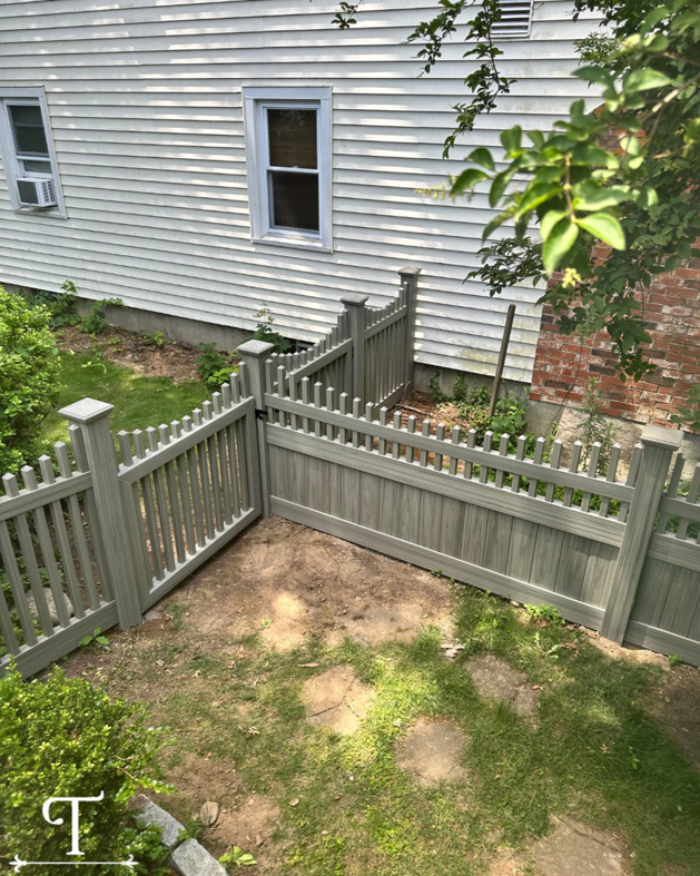 A newly installed grey picket-style fence with a gate, providing backyard enclosure by Teto's Fence Installation in Bridgeport, CT.