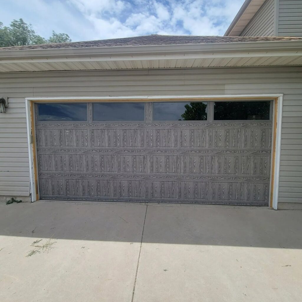 A modern grey wood-grain garage door with top windows, installed by Your Other Front Door LLC in Lakewood, CO.