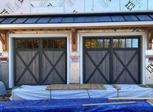 Two grey wood-look garage doors with windows installed on a new construction home by Summers Garage Door in Denver, CO.