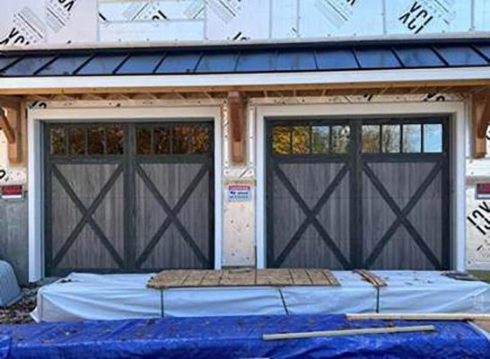 Two grey wood-look garage doors with windows installed on a new construction home by Summers Garage Door in Denver, CO.