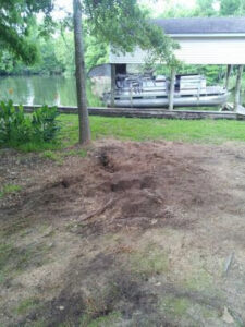 Ground preparation and landscaping work in progress near a tree and water by DLC Service in Kenner, LA.