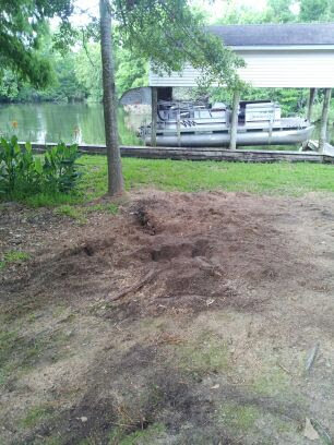 Ground preparation and landscaping work in progress near a tree and water by DLC Service in Kenner, LA.