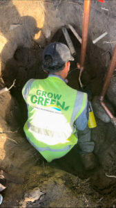 A Grow Green Irrigation Svc technician repairing an irrigation system in a trench in Brighton, CO.