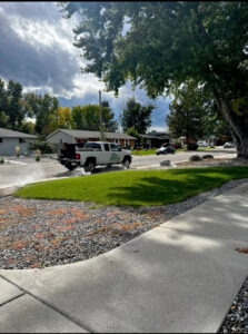A Grow Green Irrigation Svc truck applying a lawn treatment on a residential street in Brighton, CO.