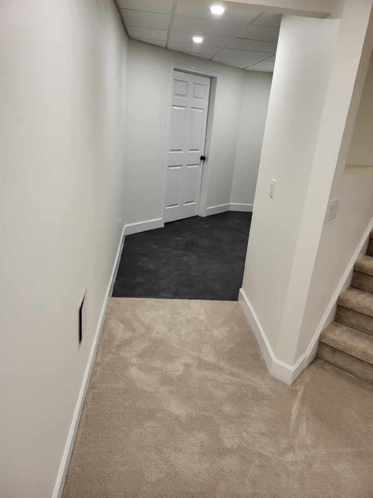 A hallway and stairs featuring new beige carpet installed by Christie Carpets & Blinds in Rochester, NY