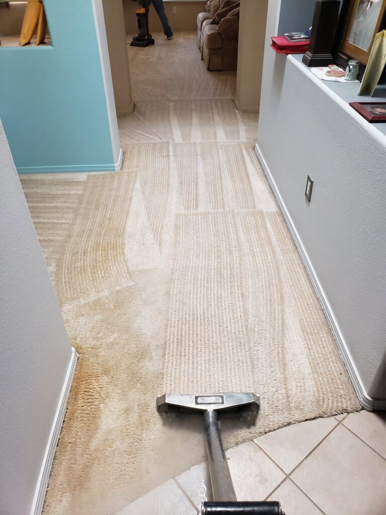 A hallway carpet being cleaned, showing the clean and dirty sections, with another cleaner in the background by Steamaway Carpet Cleaning in Albuquerque, NM.