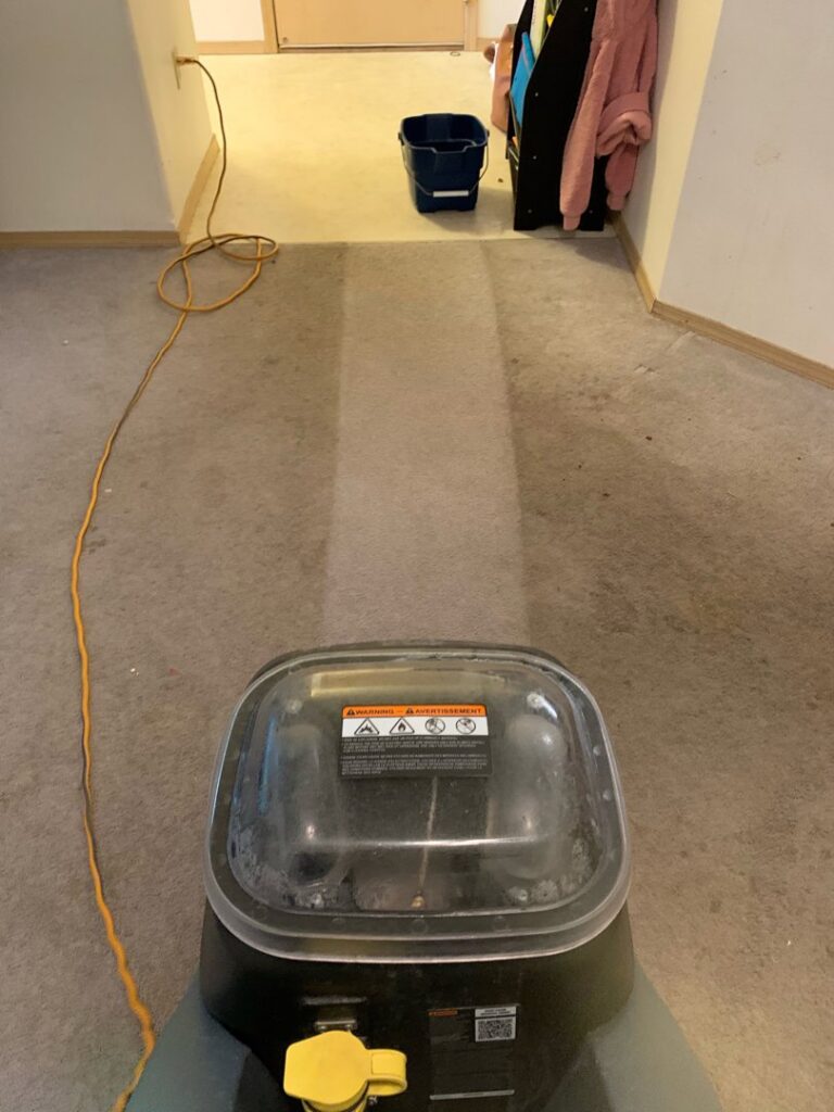 A carpet cleaning machine cleaning a hallway, showing a clear before-and-after line by Alaska Floor Care Specialists in Fairbanks, AK.