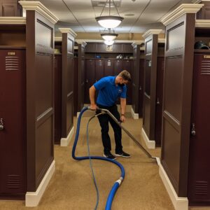 A technician from North Seattle Carpet Cleaning cleaning a carpeted hallway in a locker room area in Seattle, WA