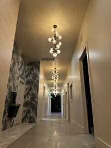 A long hallway illuminated by multiple decorative light fixtures installed by Premier Power in Edmond, OK.