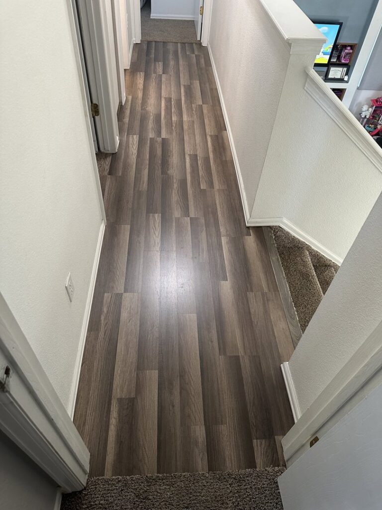 A residential hallway featuring new hardwood flooring and carpeted stairs by H&J Brothers Ltd in Colorado Springs, CO.