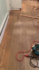 Ongoing hardwood floor installation in a hallway with tools visible, by Isad Home Floor in Bridgeport, CT.