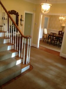 Wall-to-wall carpet in a hallway extending to a staircase runner installed by Carpet Binding Company in Charlotte, NC.