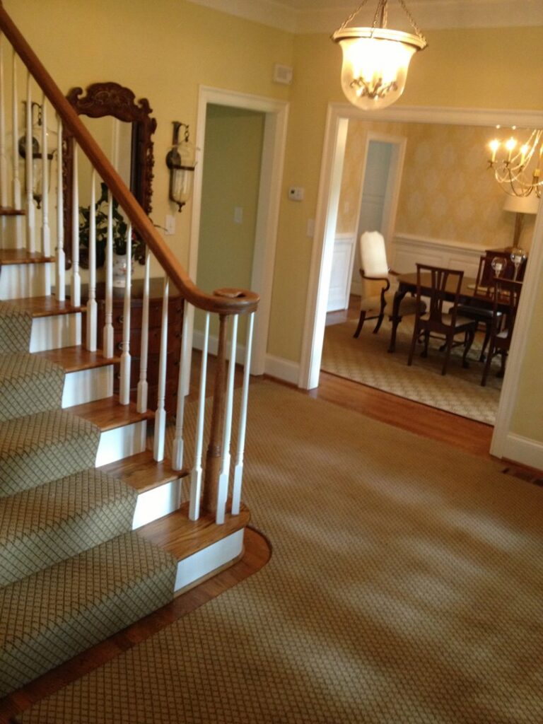Wall-to-wall carpet in a hallway extending to a staircase runner installed by Carpet Binding Company in Charlotte, NC.