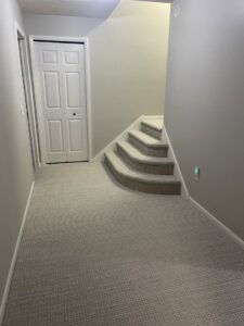 Newly installed light-colored carpet on a hallway and staircase by West Michigan Flooring & Interiors in Grand Rapids, MI.
