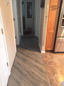 Hallway with newly installed vinyl plank flooring transitioning to another room by Alaska Flor-Wall, Inc. in Anchorage, AK.