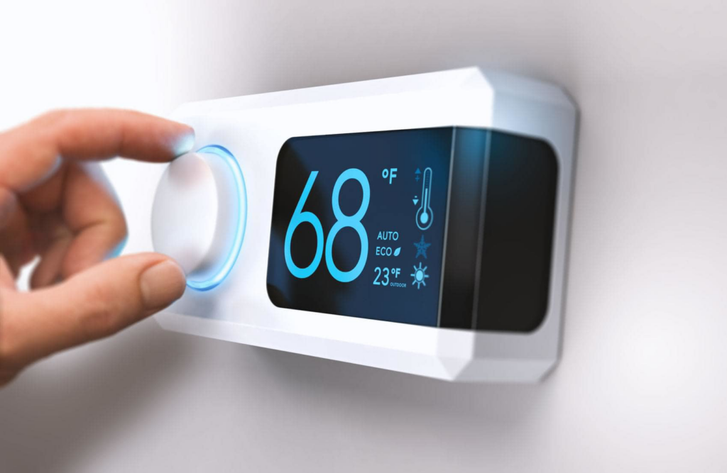 A hand adjusting a modern digital thermostat for heating and cooling at Carpenter Heat Air Electrical in Henderson, TN.