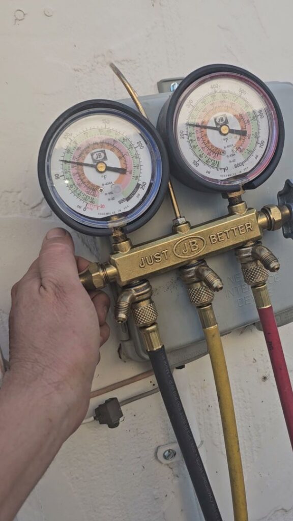 A technician's hand adjusting refrigerant gauges during an HVAC or refrigeration service by Henry Refrigeration & Hvac Utah in Ogden, UT.