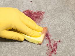 A gloved hand cleaning a red stain from a carpet, demonstrating professional carpet cleaning services by Carpet Cleaner Staten Island in Staten Island, NY.