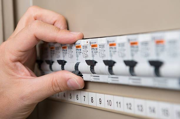 A hand flipping a circuit breaker in an electrical panel, a service provided by Faith Electrical Service in Billings, MT.