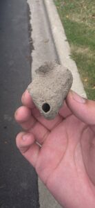 A hand holding a small, removed mud dauber wasp nest, demonstrating a pest control service by Pro Barrier Pest Control LLC in Aurora, IL.