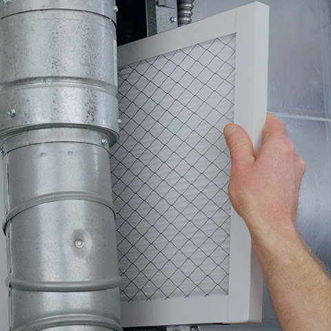 A hand inserting a clean air filter into a duct, demonstrating HVAC maintenance by Mid-City HVAC, INC. in Chicago, IL.