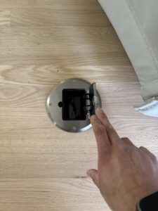 A hand opening a floor electrical outlet installed by LivElectric in Garner, NC.