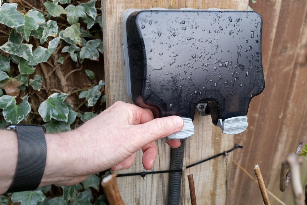 A hand operating an outdoor electrical junction box, showing electrical work by Polk Electric, LLC in Rock Hill, SC