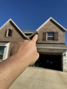 A hand pointing towards a roofline, indicating an inspection or identified problem area by Dallas Fort Worth Wildlife Control in Hurst, TX.