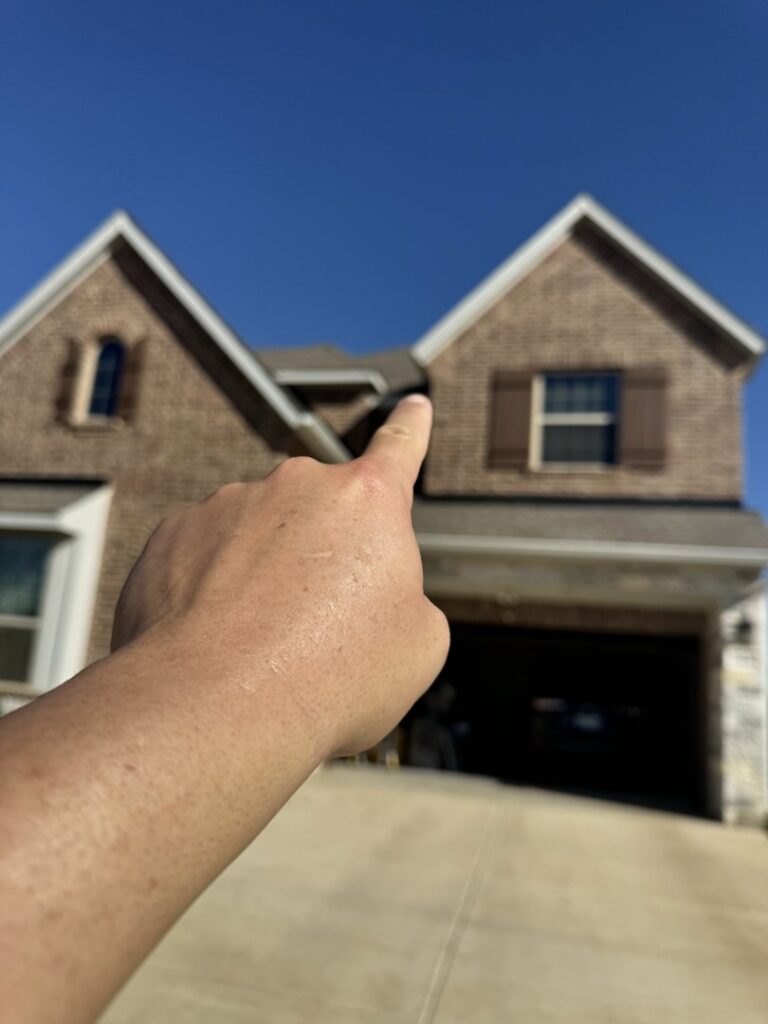 A hand pointing towards a roofline, indicating an inspection or identified problem area by Dallas Fort Worth Wildlife Control in Hurst, TX.
