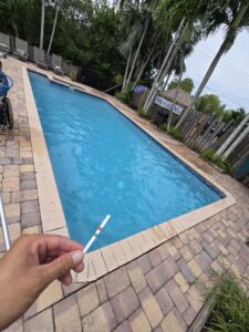A professional from Summer Breeze Pool Services testing pool water with a test strip in Fayetteville, GA.